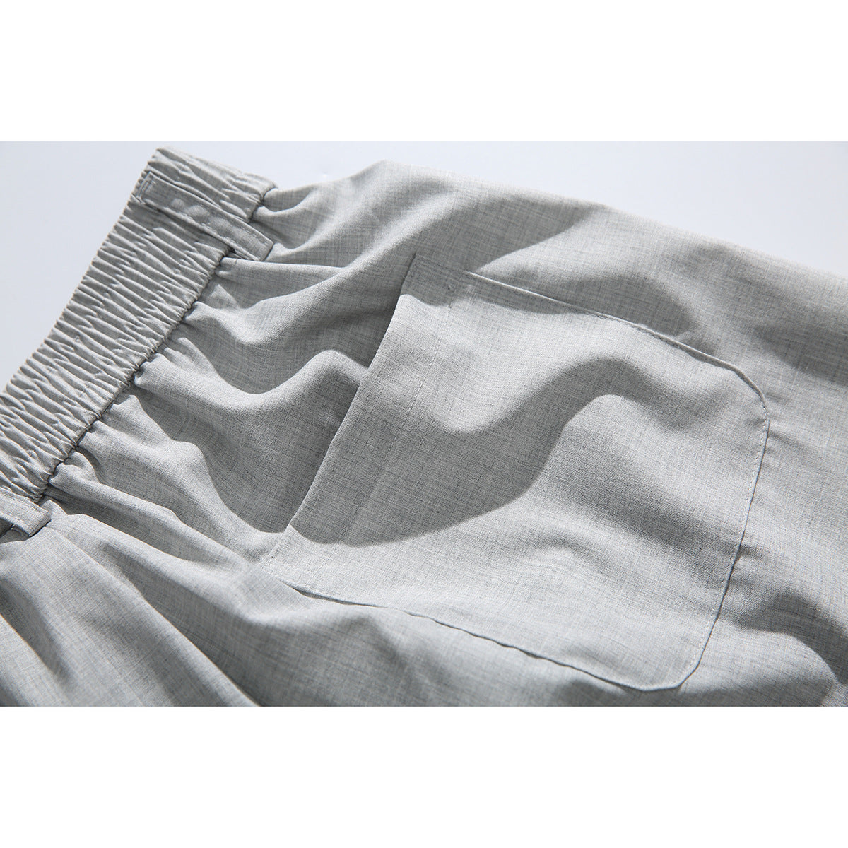 Close-up of the light gray shorts' gathered waistband and large rear patch pocket.