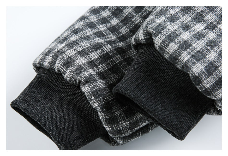 Close-up of black ribbed cuffs beside the charcoal and gray plaid jacket fabric.