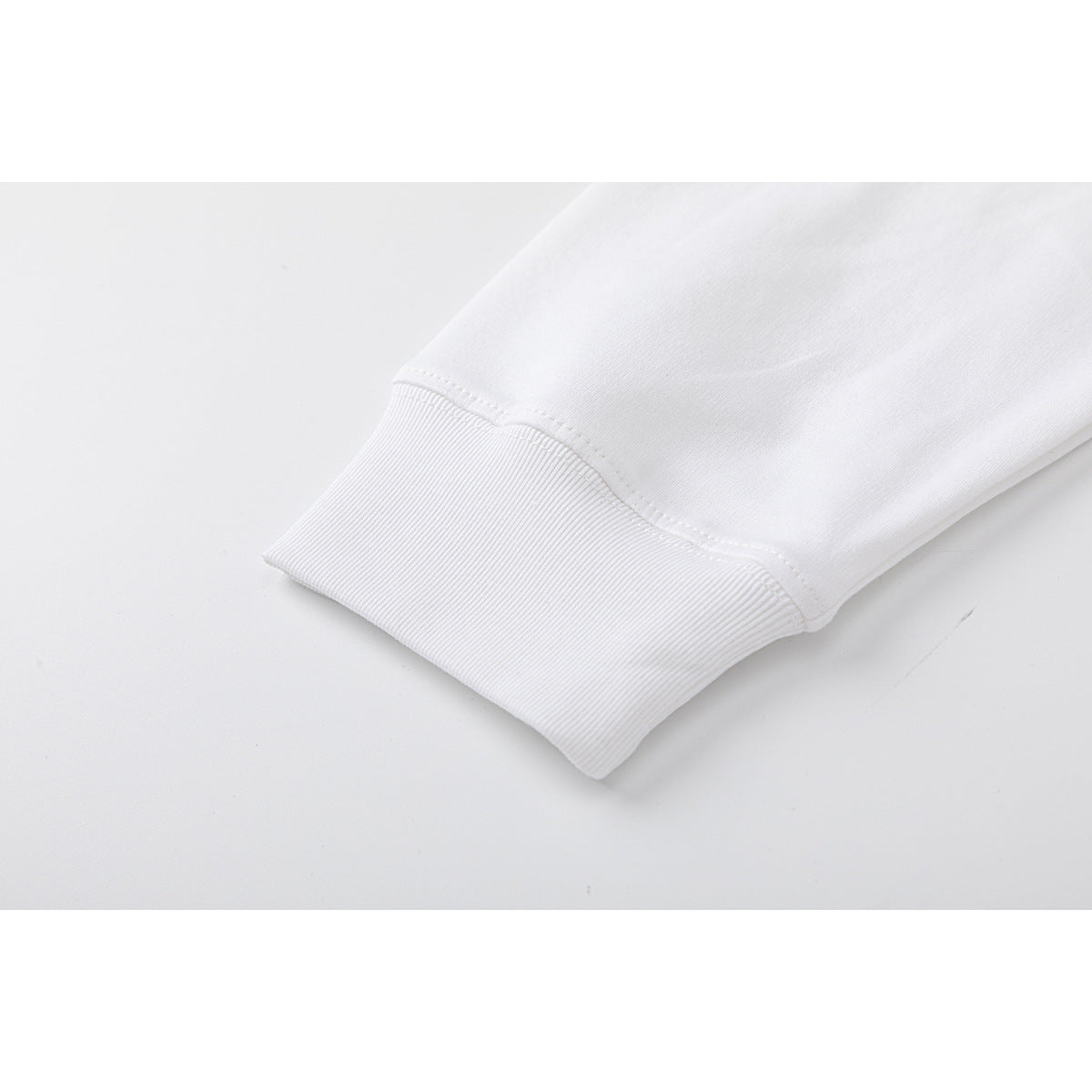Close-up of a white sleeve ending in a wide ribbed cuff with visible stitching.