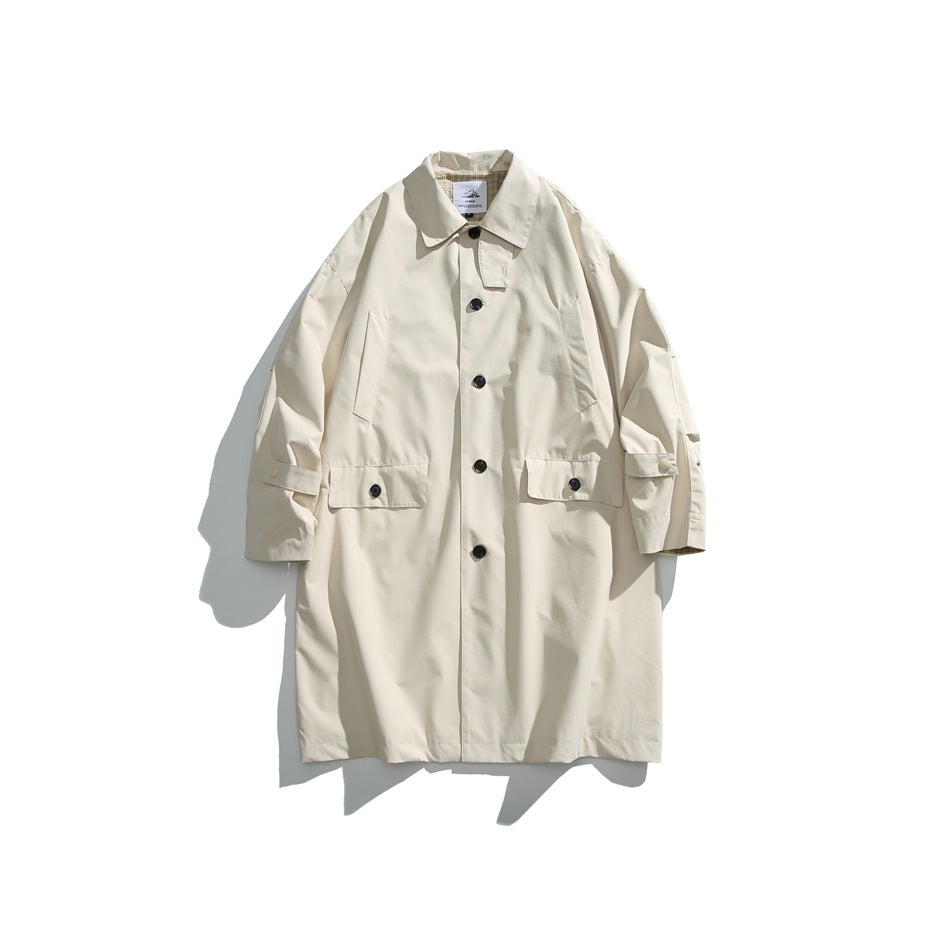 Front view of an ivory long coat with a collar, black buttons, large flap pockets, and adjustable sleeve tabs.