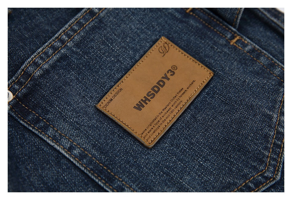 Close-up of a tan branded leather patch stitched onto dark blue denim.