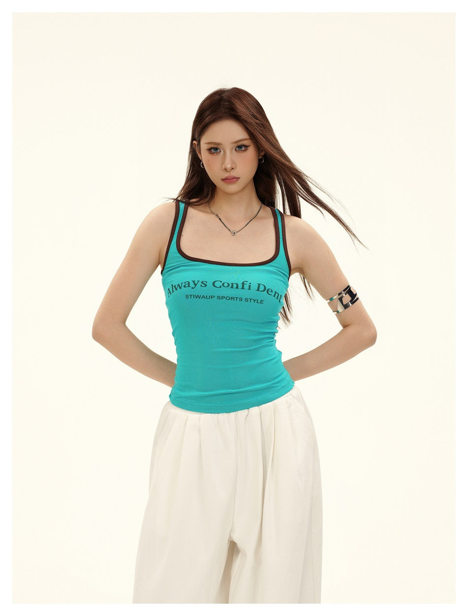 Front view of a model wearing a turquoise tank with dark trim and white pants.