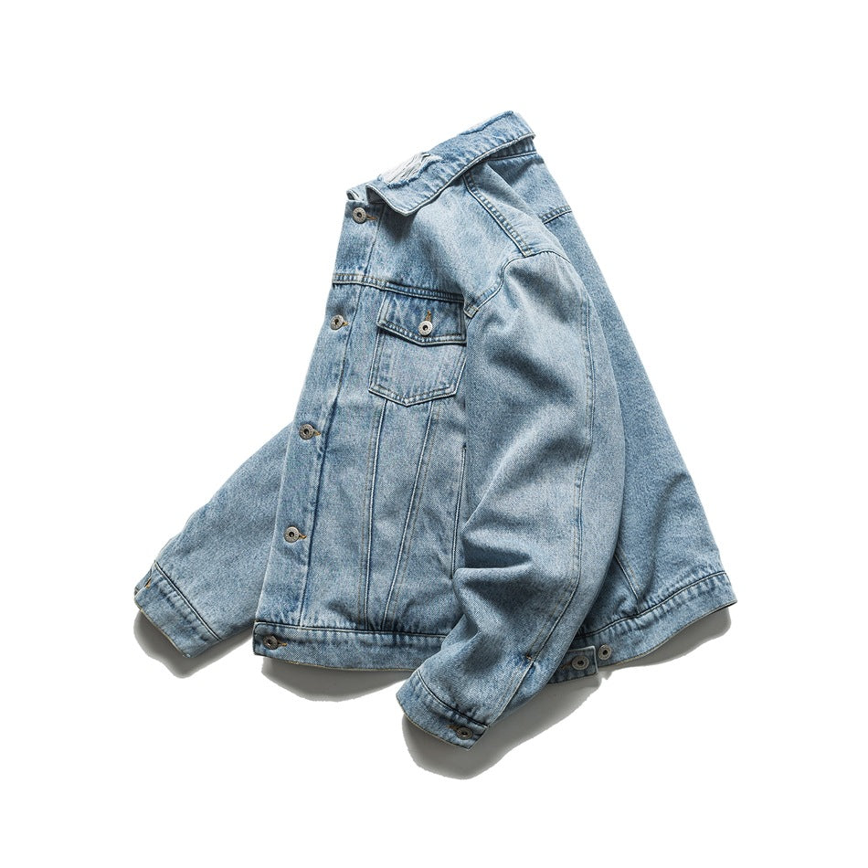 Light blue denim jacket arranged at an angle, showing its button front, pointed collar and chest pocket.