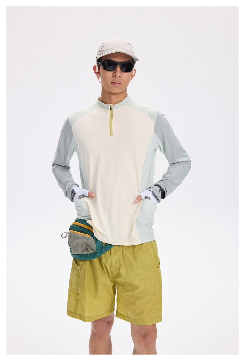 A man wears a cream and pale blue long-sleeve cycling top with a short yellow front zipper and side pockets.