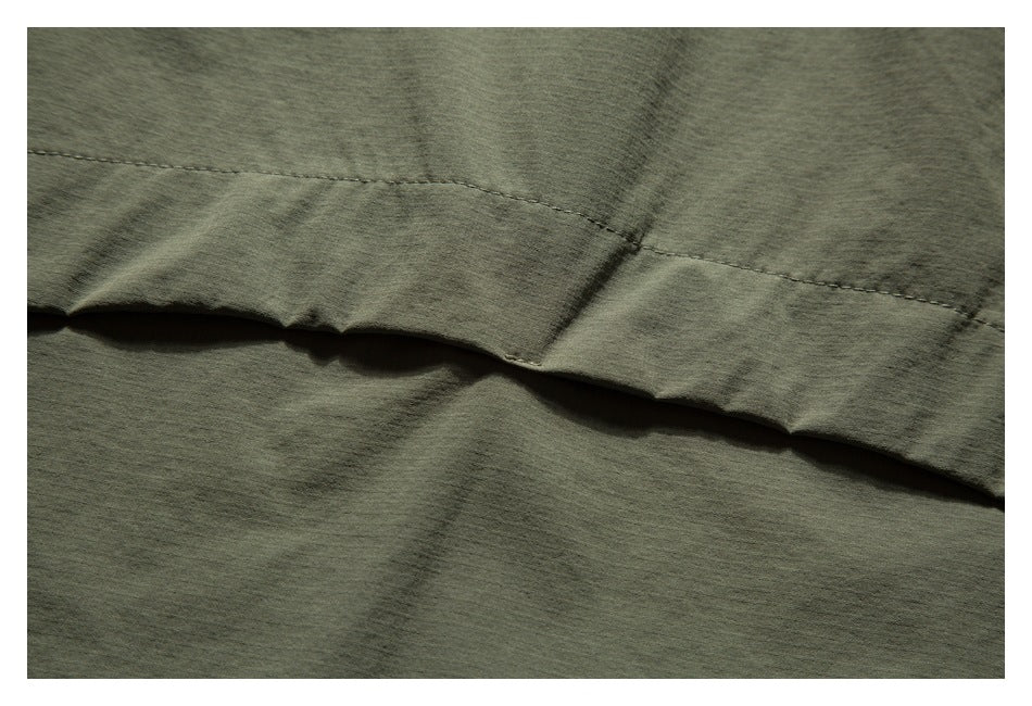 Close-up of an olive-green garment hem with visible stitching and folded fabric.