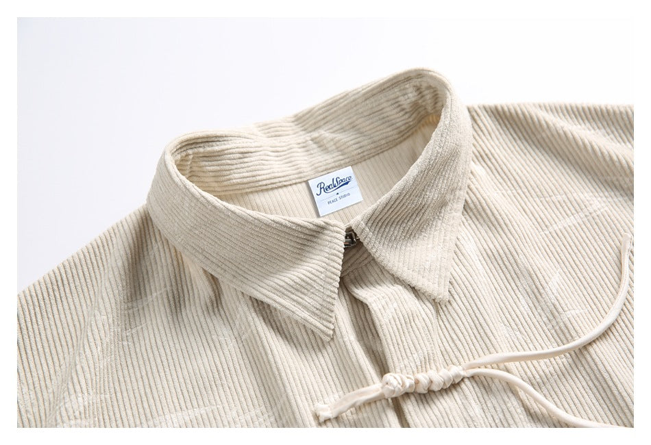 Close-up of a cream tunic's ribbed collar, neck label and upper frog closure.