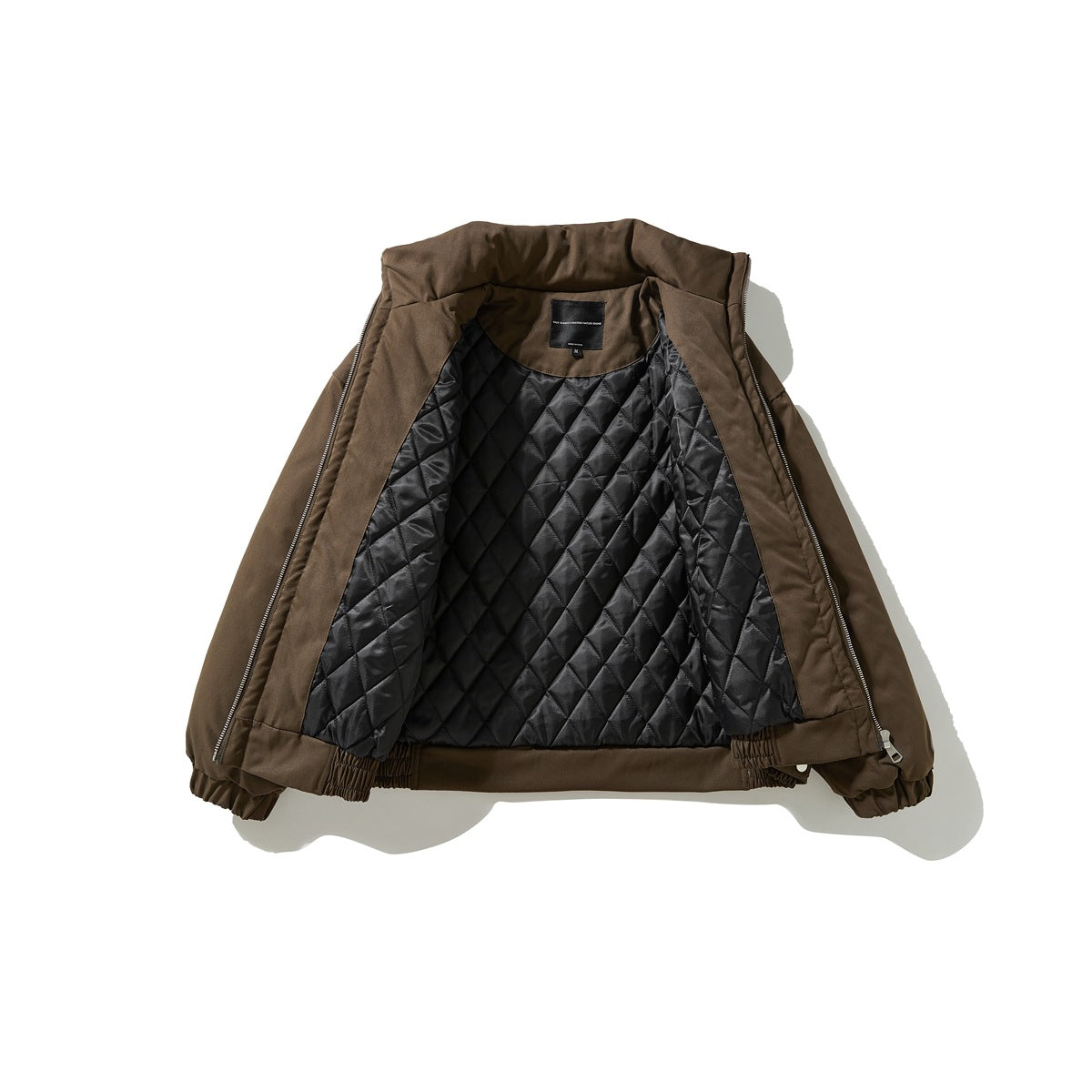 Brown zip jacket laid open, showing its black diamond-quilted lining and inner neck label.