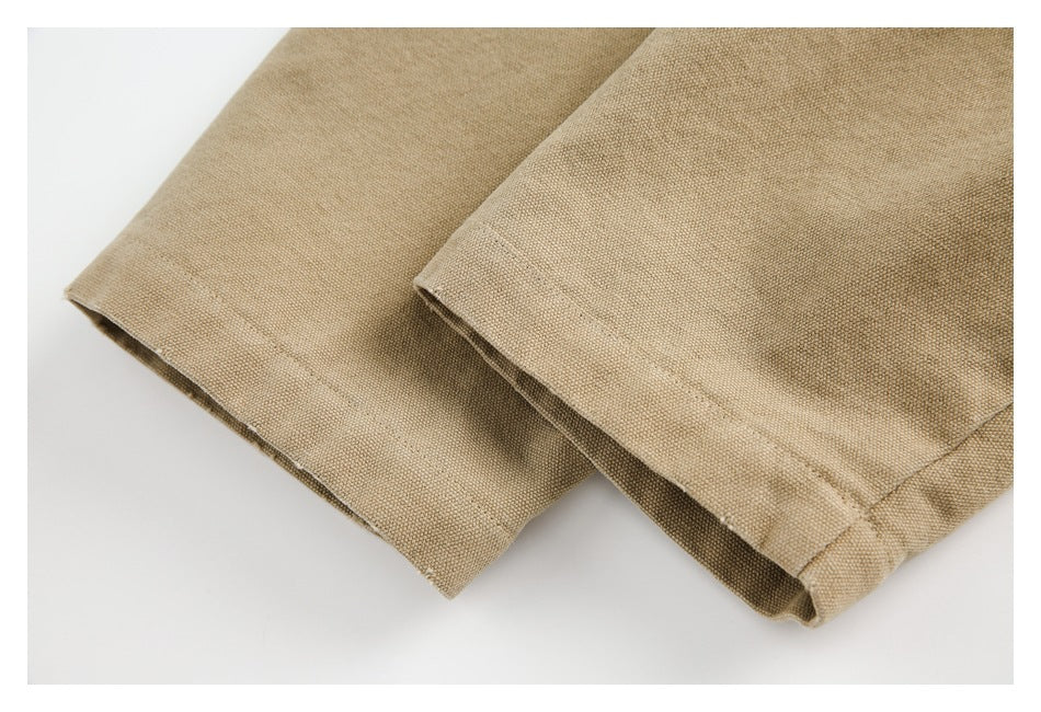 Close-up of tan woven garment fabric with stitched hems and overlapping edges.