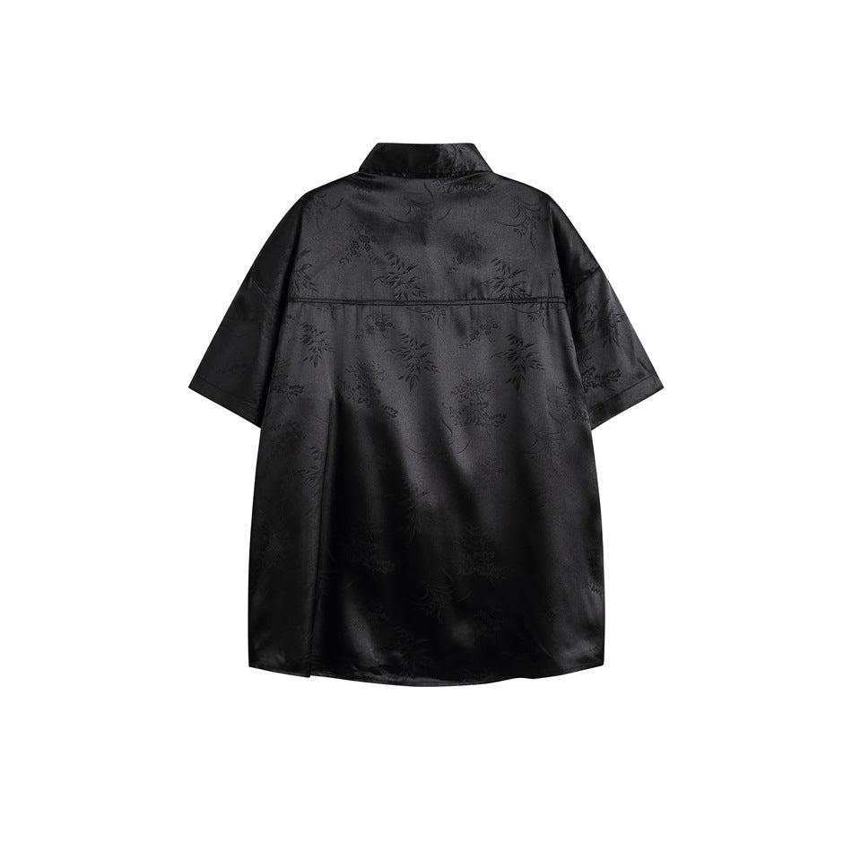 Back view of a black short-sleeve collared shirt with a subtle tonal floral pattern.
