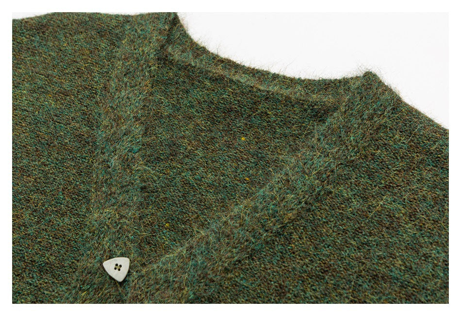 Close-up of a mottled teal-brown knit neckline with a small cream triangular button.