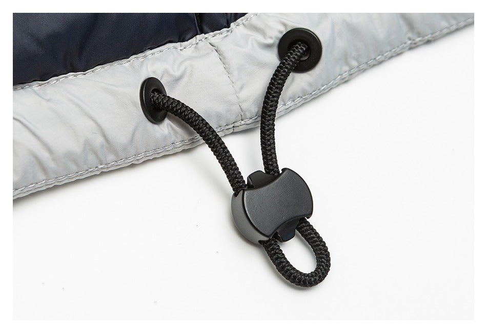 Close-up of a black drawcord toggle threaded through eyelets on the light gray hem of a jacket.