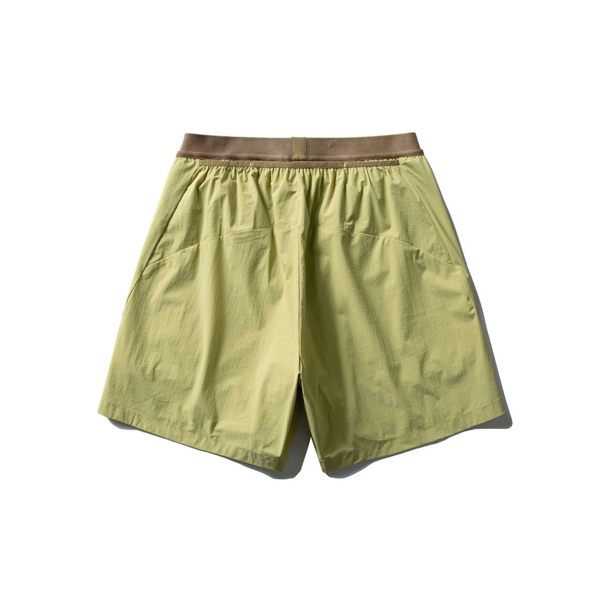 Back view of loose yellow-green shorts with a brown waistband and curved rear panel seams.