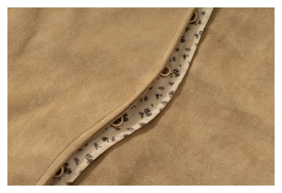 Close-up of the tan jacket's button placket, showing cream fabric with a small purple floral print beneath it.