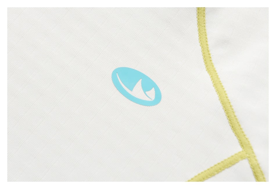 Close-up of a small turquoise emblem and yellow seam trim on white fabric.