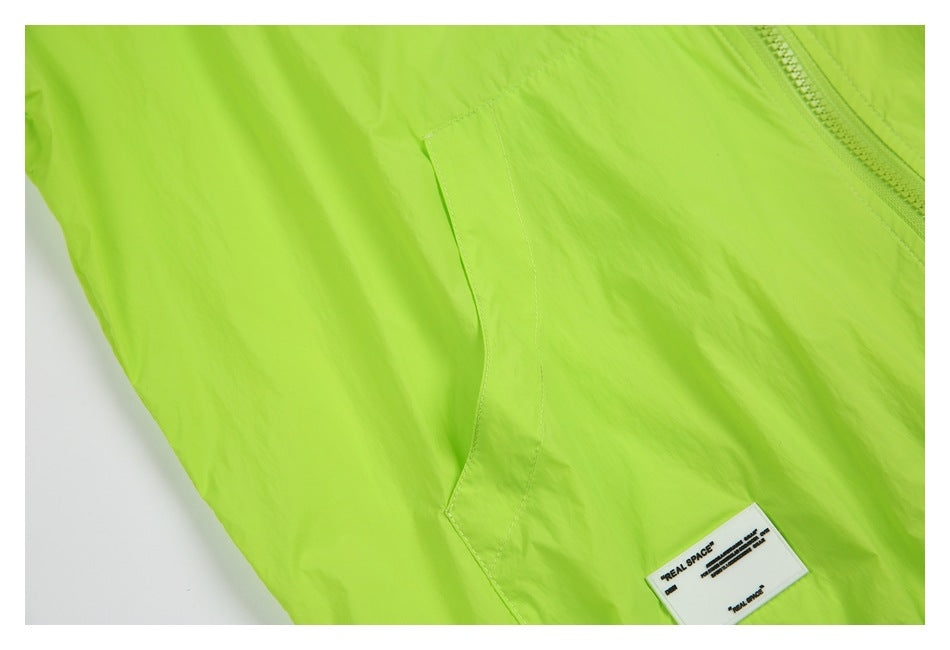Neon lime garment detail showing a curved seam, zipper edge, and sewn REAL SPACE label.