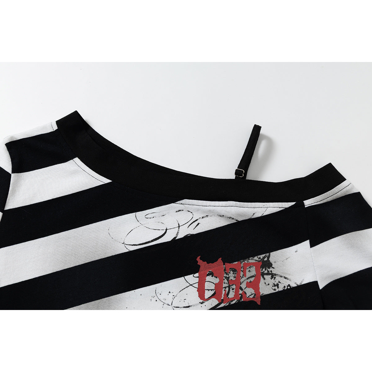 Close-up of the shirt’s wide neckline, thin adjustable strap, stripes, and distressed chest graphic.