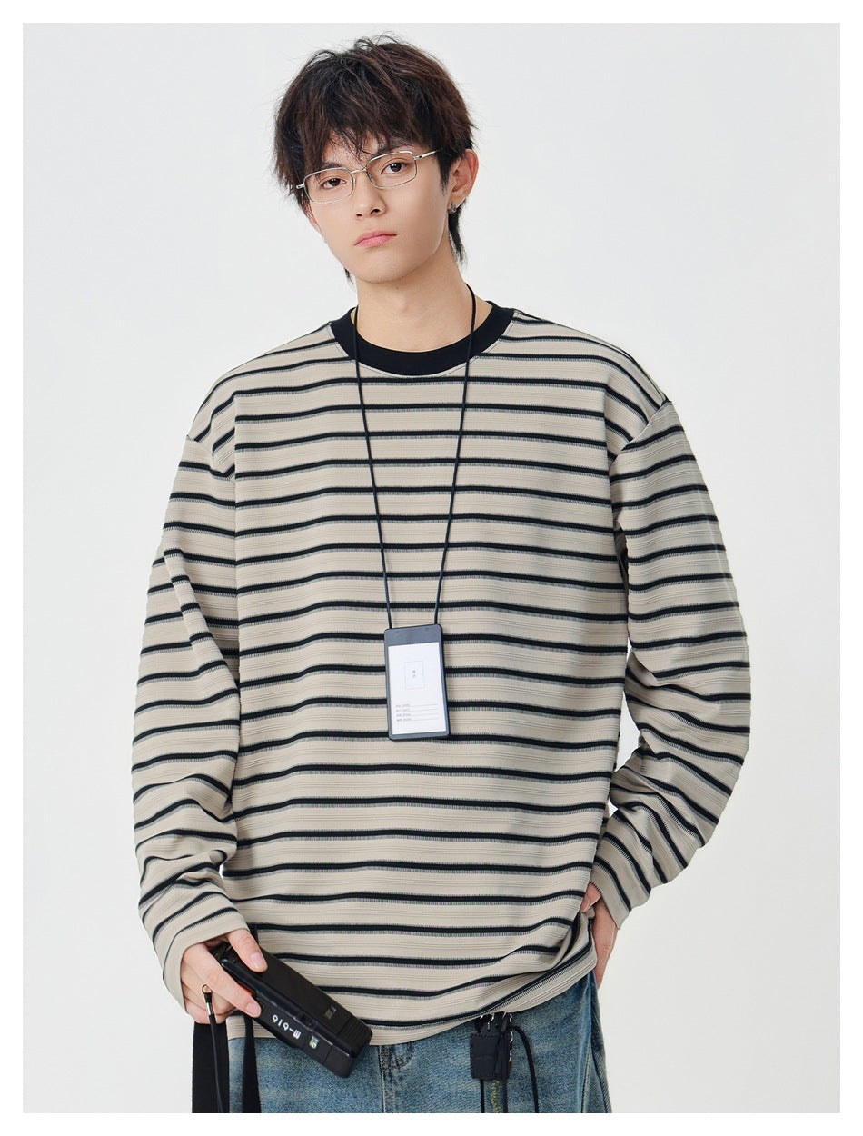Model wearing khaki long-sleeve striped crew-neck top with black stripes and black collar, with jeans