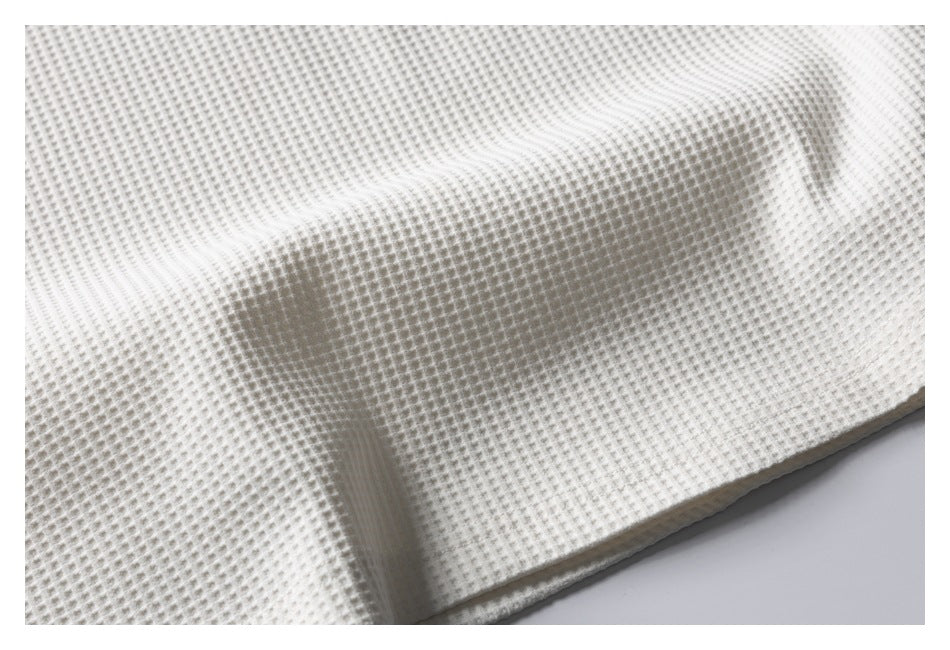 Close-up of the ivory garment's raised waffle-knit texture and folded fabric.