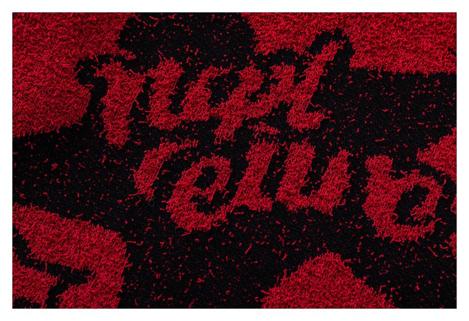 Close-up of the scarf's red and black textured lettering pattern, shown within a white border.