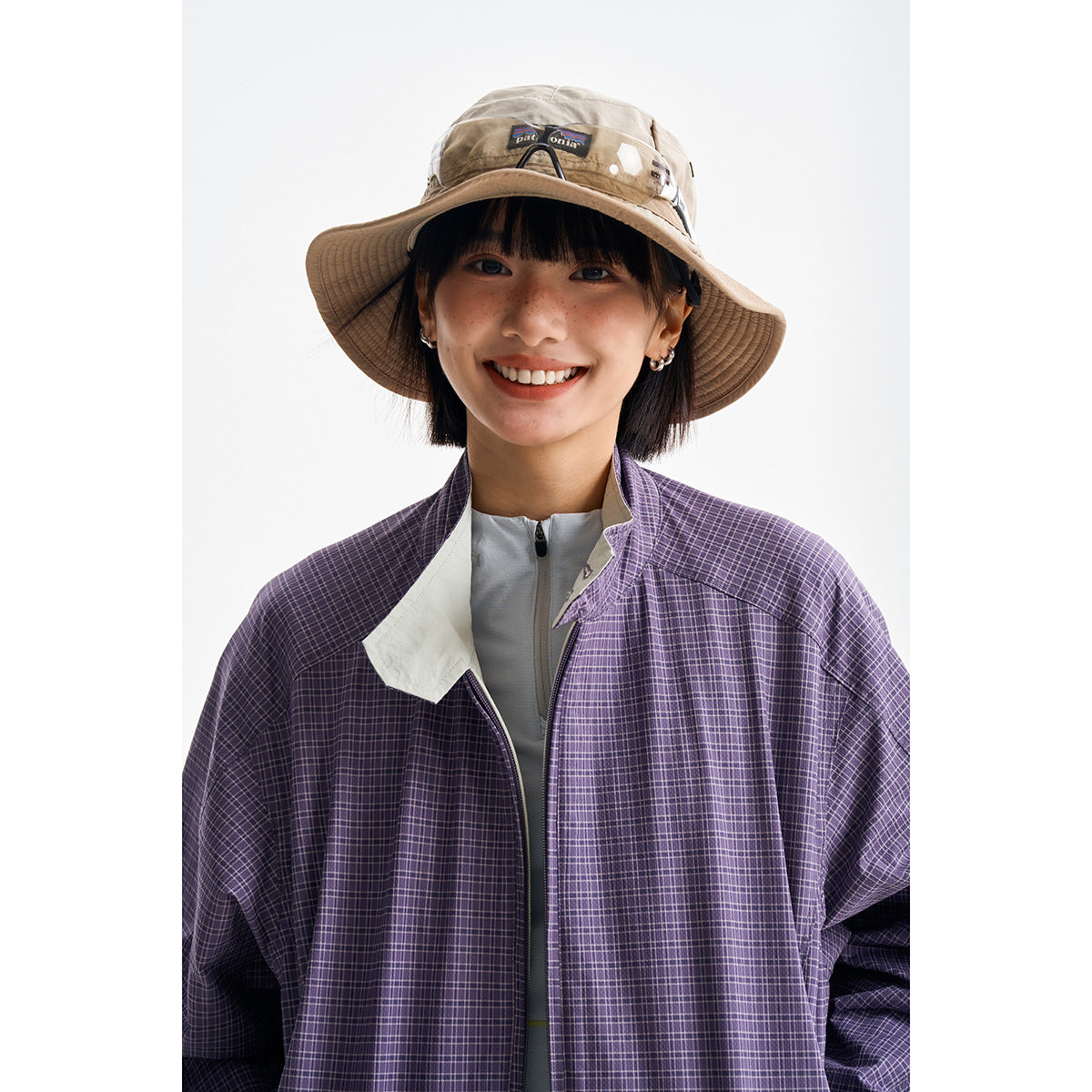 Close-up of a model wearing a purple plaid jacket with a pale contrast collar and front zipper.