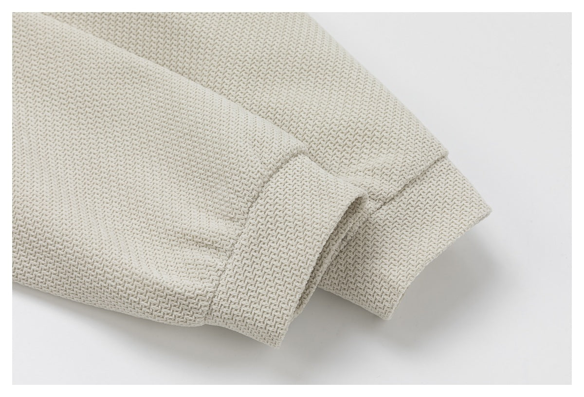 Close-up of the ivory jacket's textured sleeve cuffs and overlapping fabric edges.