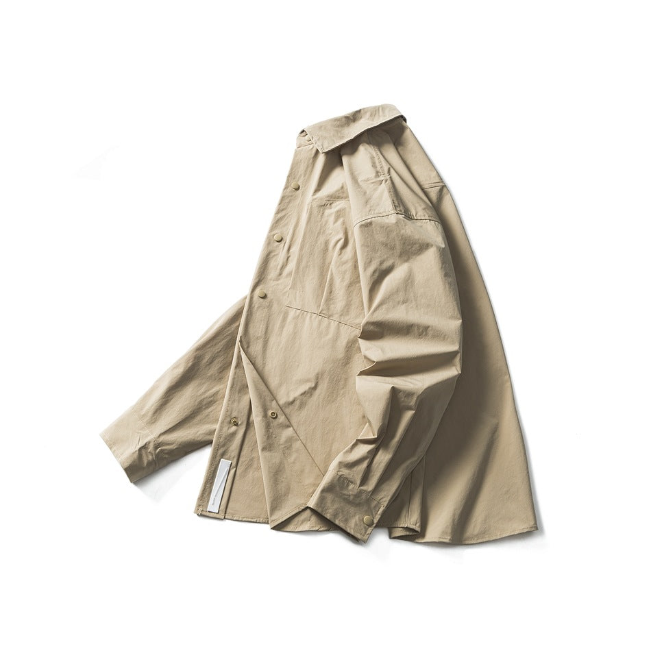 Angled view of a beige long-sleeve shirt showing its button front, pointed collar, chest pocket, and button cuffs.