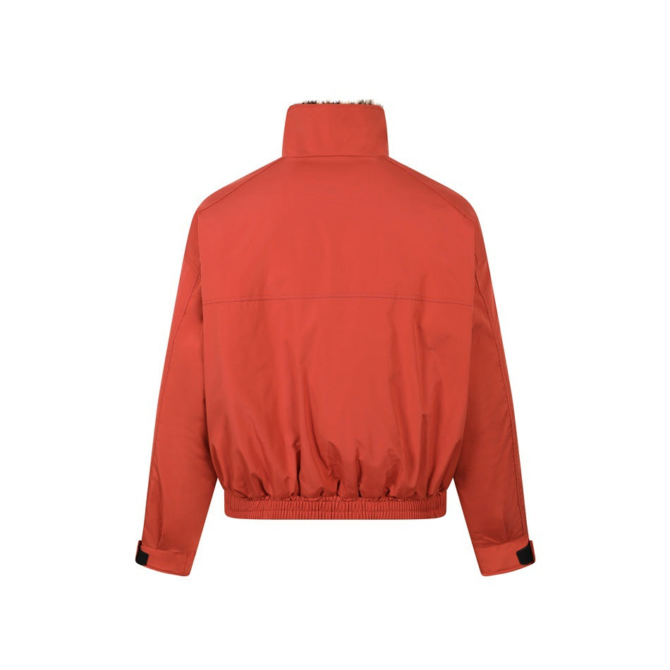 Back view of a rust-red jacket with a high collar, long sleeves, adjustable cuffs, and an elasticized hem.