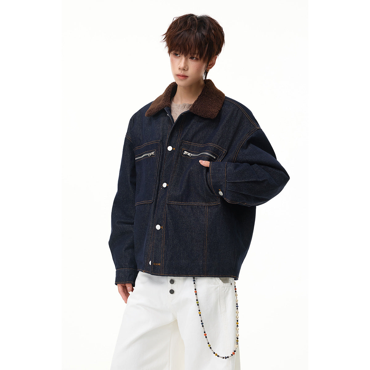 Angled view of a model wearing an oversized dark indigo denim jacket with a brown collar and zip chest pockets.
