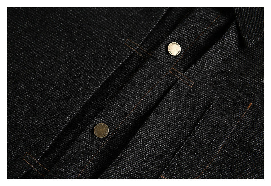 Close-up of a black jacket front placket with brass-tone buttons and orange contrast stitching.