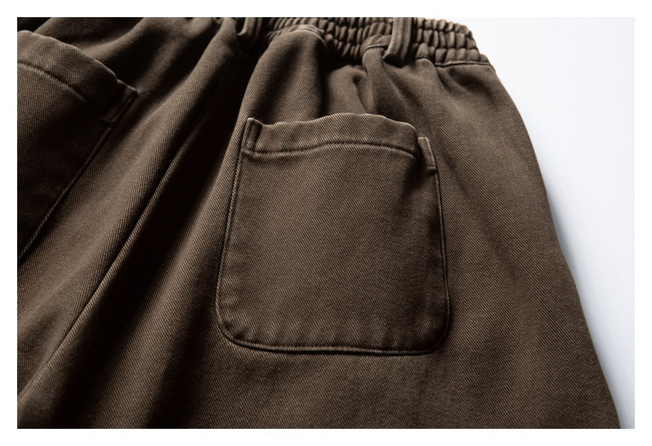 Close-up of a large patch pocket and elastic waistband on brown trousers.