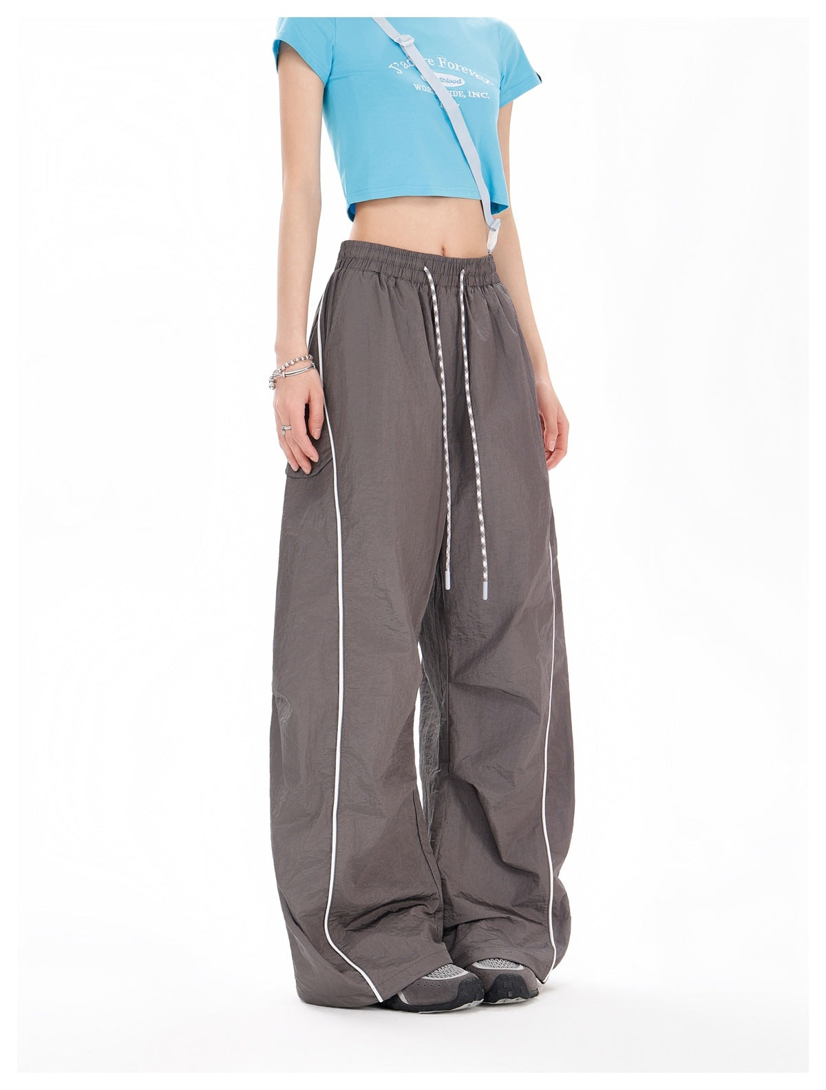 Front view of a model wearing charcoal-gray wide-leg pants with an elastic drawstring waist and white piping.