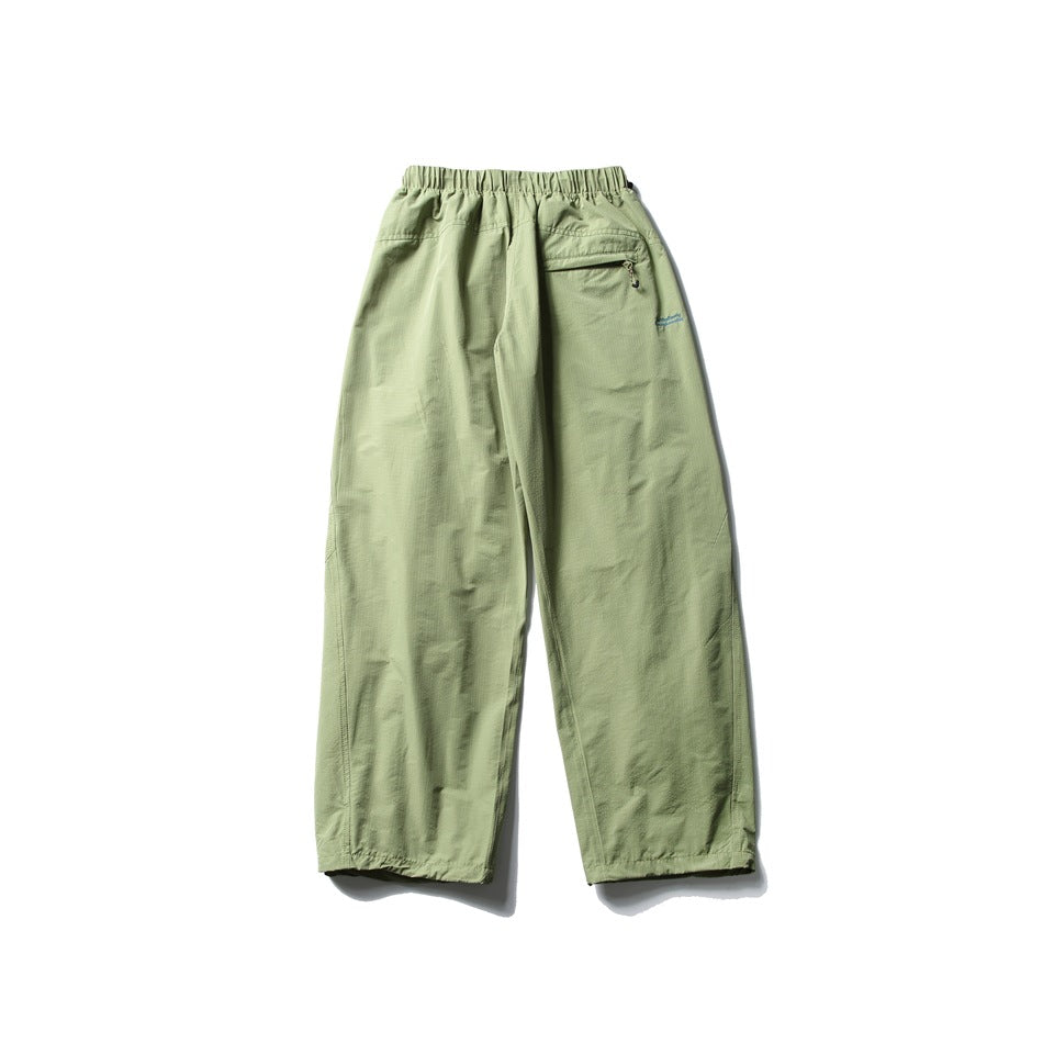 Pale sage green wide-leg pants laid flat, with an elastic waist and a small zip pocket at the back.