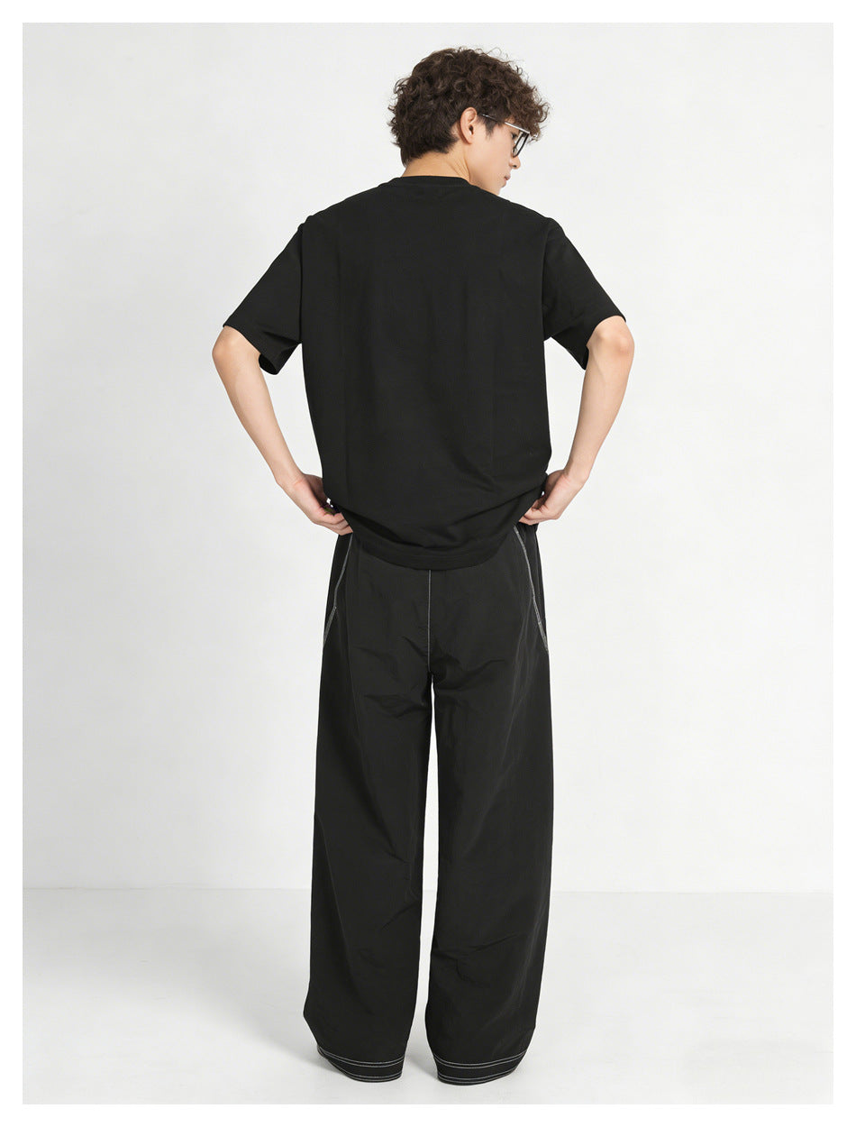 Back view of model in a black T-shirt and black wide-leg pants with white contrast stitching