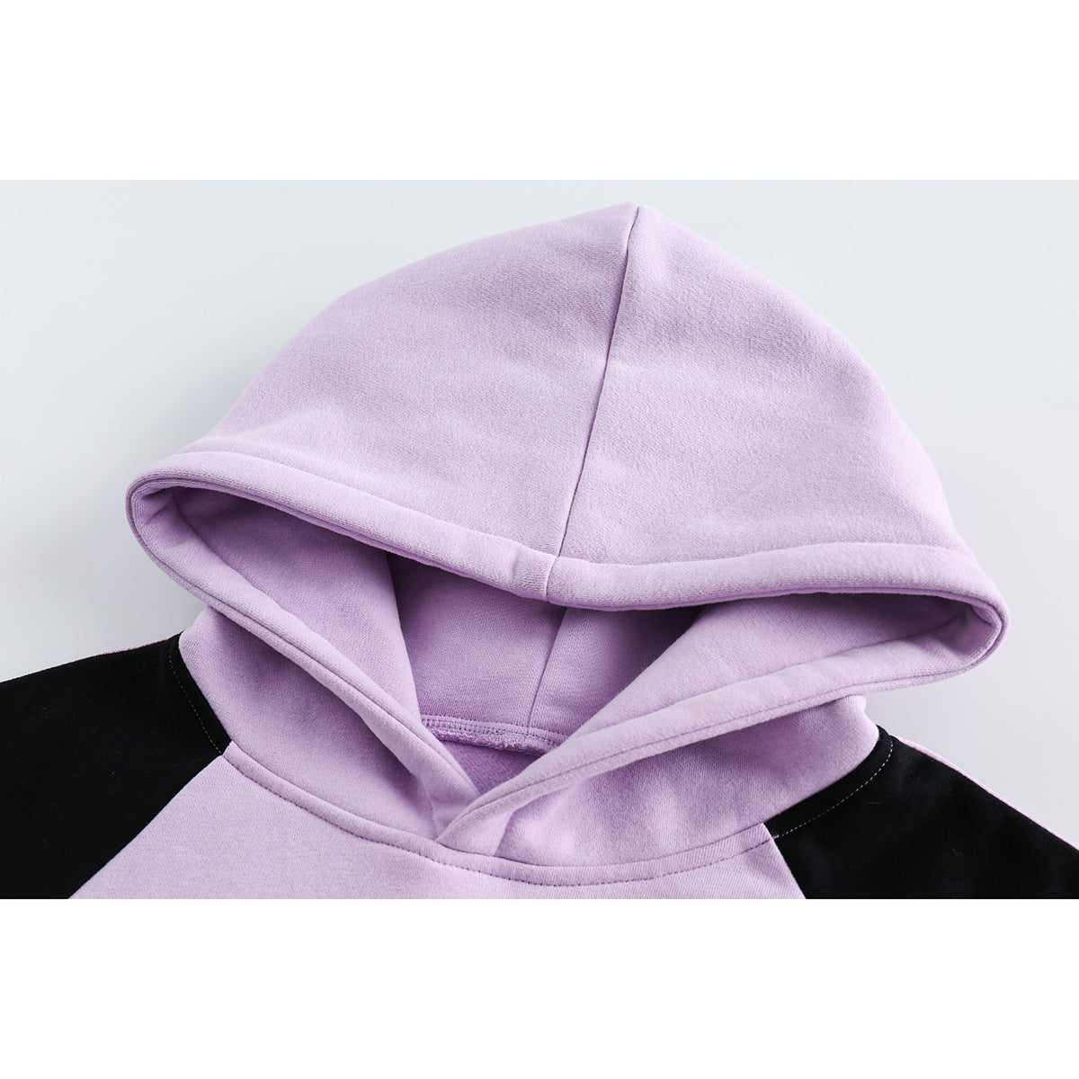 Close-up of a lavender hoodie’s lined hood and black raglan shoulder panels.