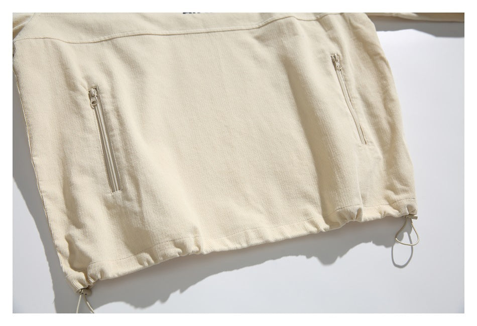 Partial back view of a cream ribbed garment with two vertical zip pockets and an adjustable drawcord hem.
