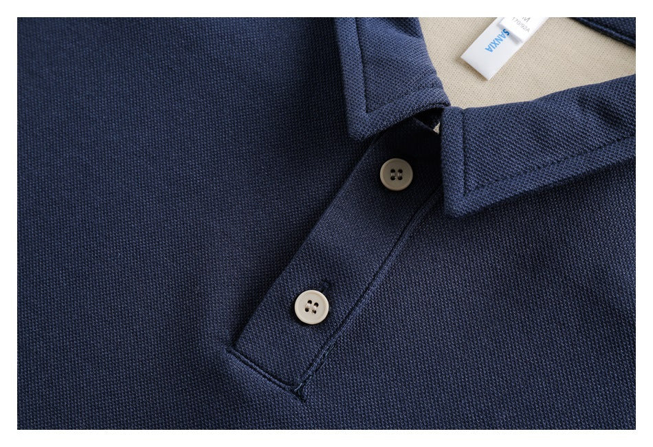 Close-up of a navy polo placket with two cream buttons, textured fabric, and a partial neck label.