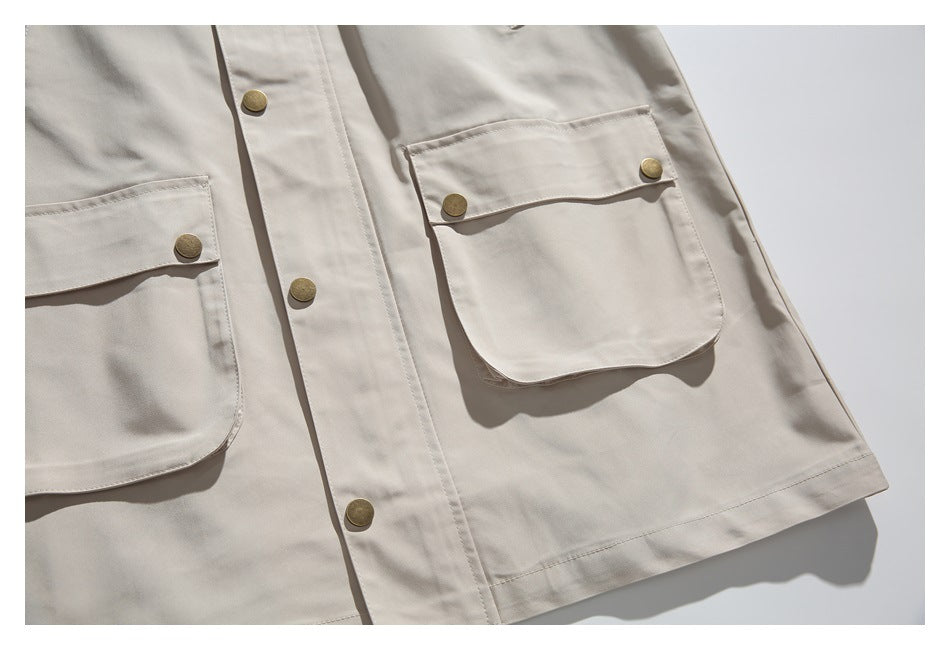 Flat-lay partial front of a light beige jacket with two flap pockets and brass-tone buttons.