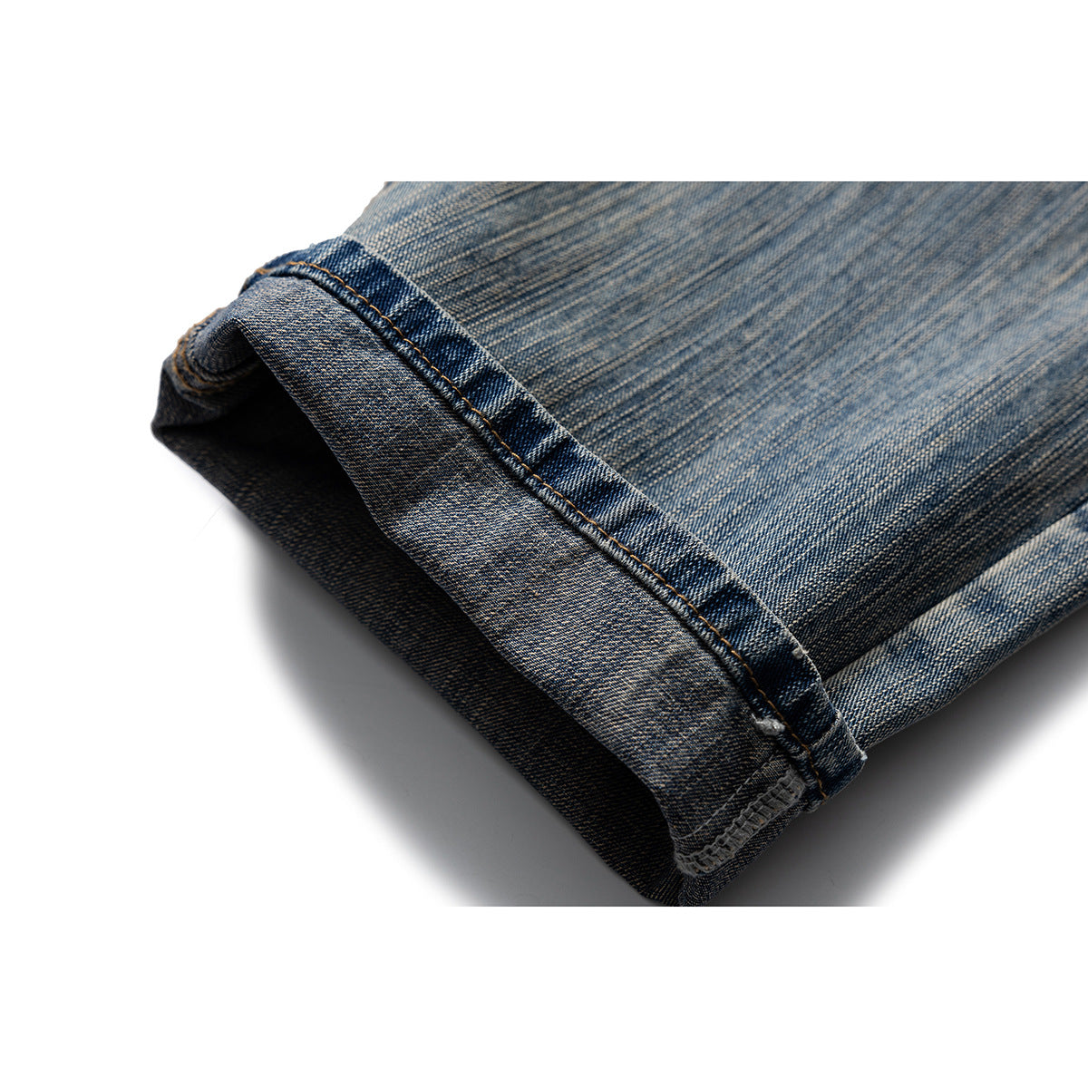 Close-up of a folded jeans leg showing the stitched denim hem and faded blue wash.