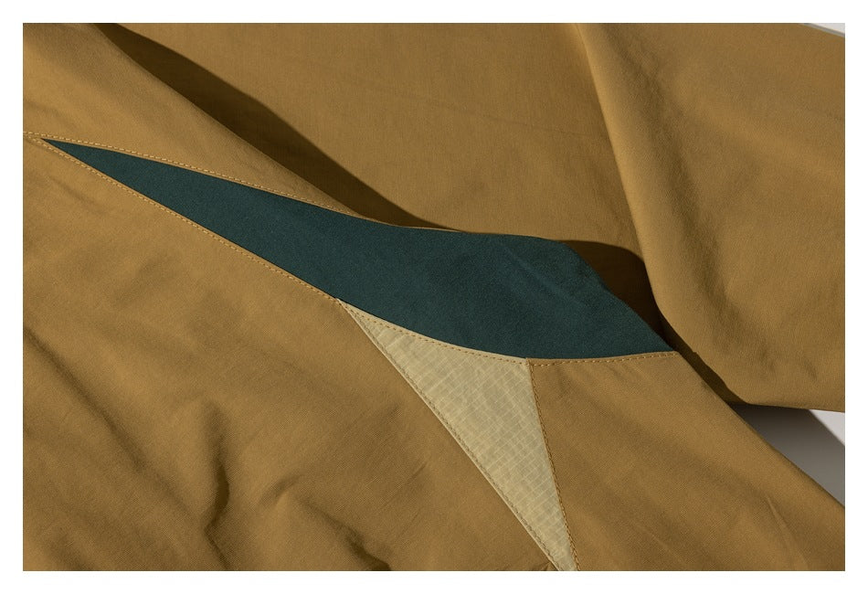 Close-up of a mustard-brown garment with a dark teal inset and a pale textured triangular panel.