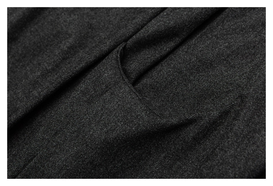 Close-up of a curved pocket opening on charcoal trousers.