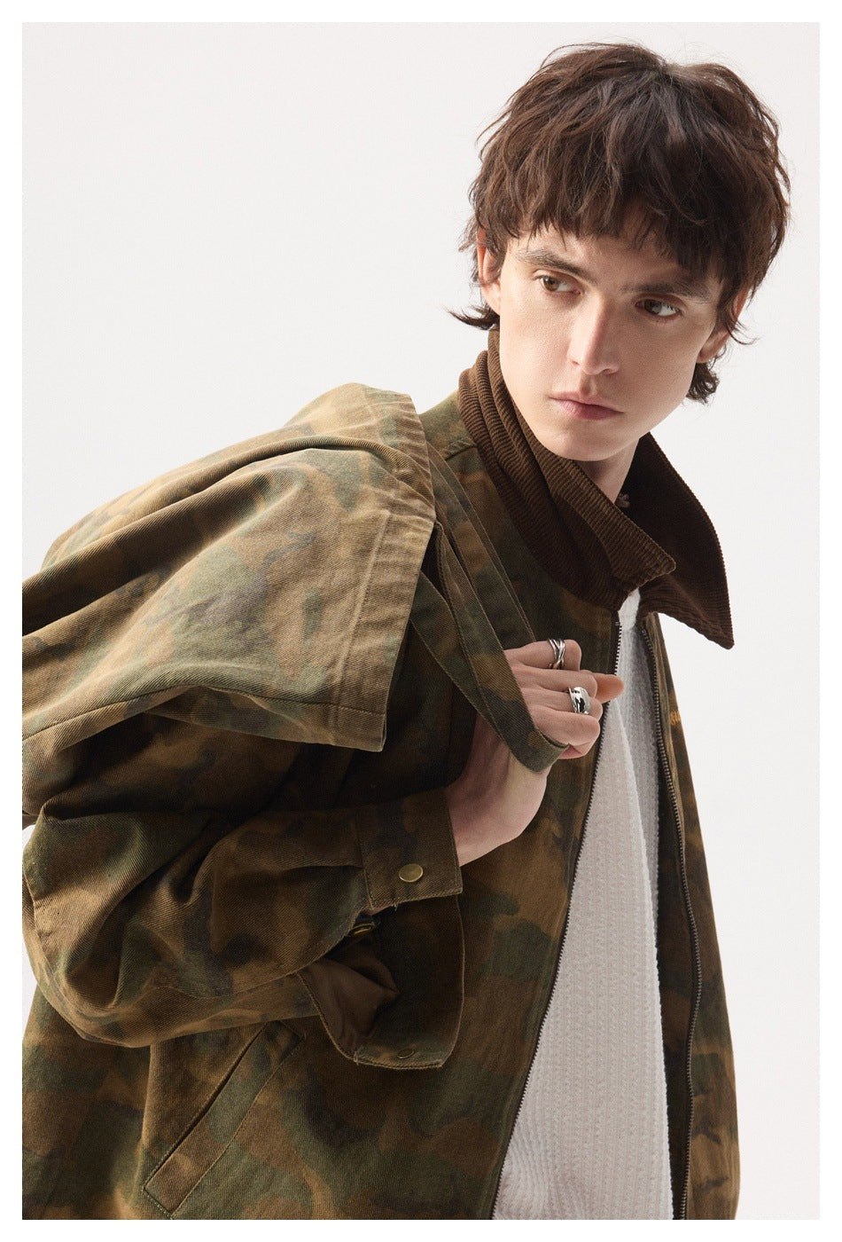Model wearing a brown-and-olive camouflage zip jacket with a dark brown corduroy collar, shown from the front at an angle.