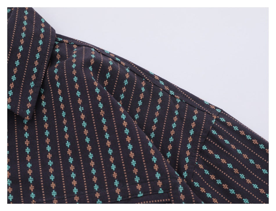 Close-up of a dark patterned shirt shoulder and sleeve with turquoise and rust motifs.