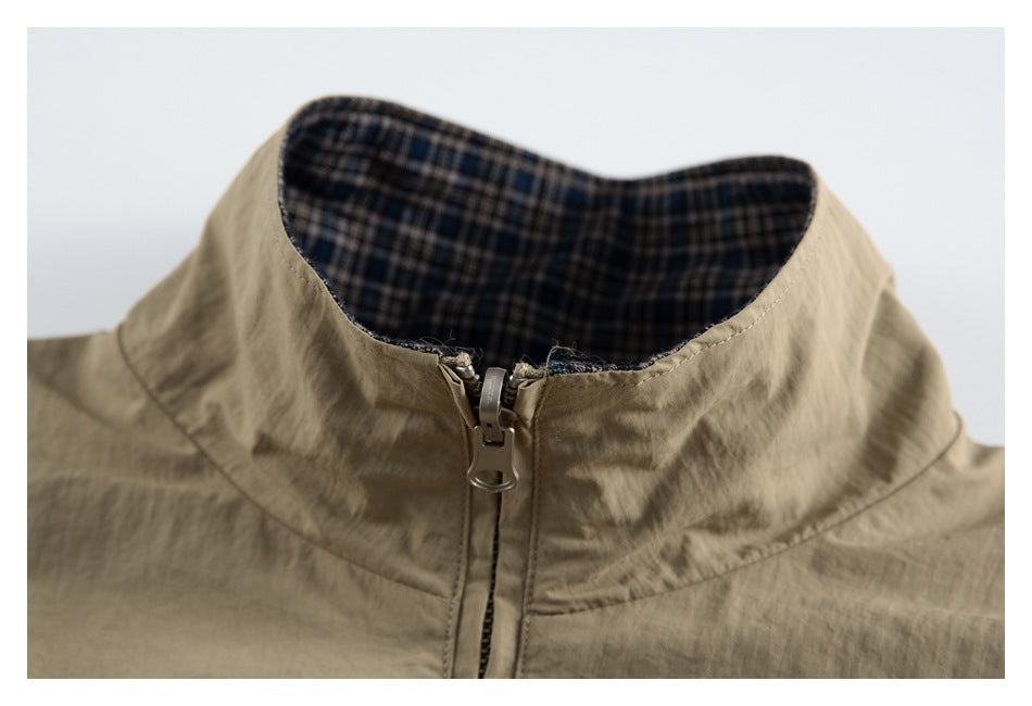Close-up of a tan jacket's zip-front stand collar with dark plaid lining.