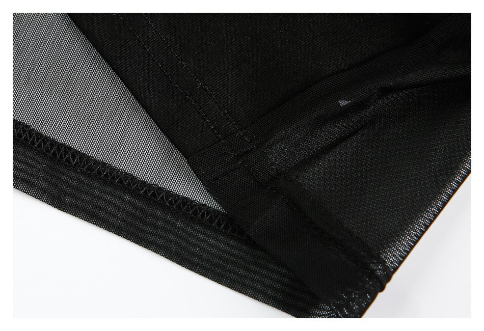 Close-up of the black top's sheer mesh panel, stitched seam, and finished edge.