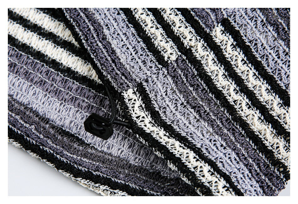 Close-up of a black drawcord and toggle against black, charcoal, and ivory striped open-knit fabric.
