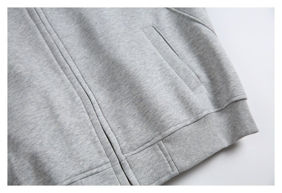 Gray heather garment detail showing a vertical front closure, angled pocket, and ribbed hem.