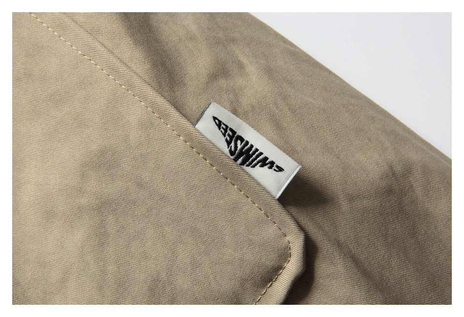 Close-up of a beige garment seam with a small white woven label bearing black text.