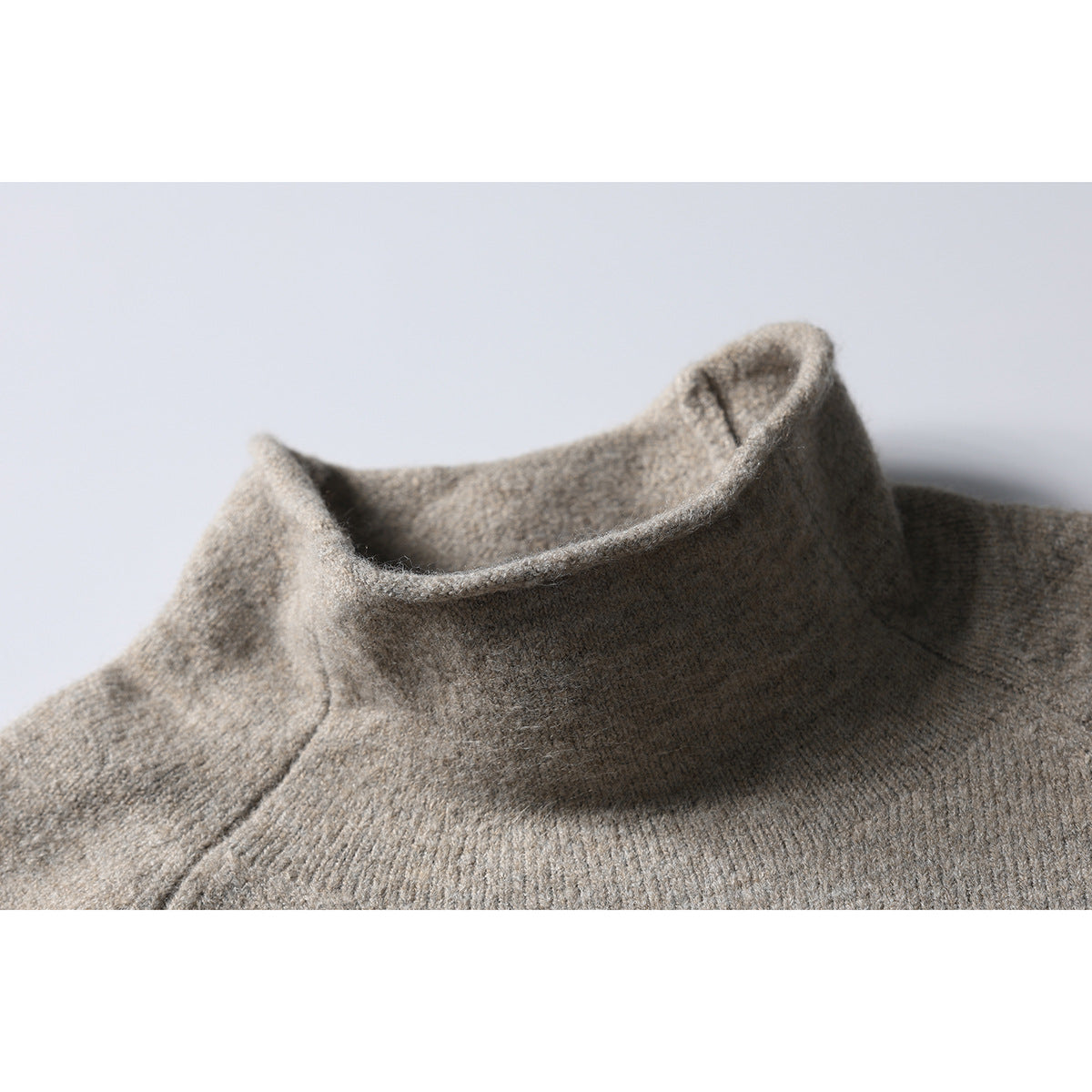 Close-up of a taupe-gray pullover's raised collar and shoulder seam.