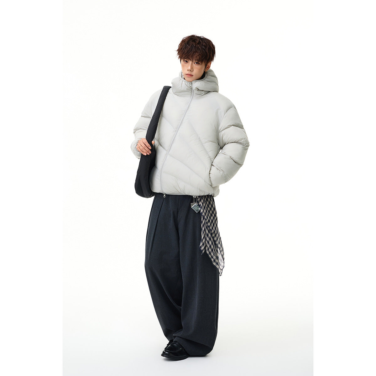 Model wearing a light gray hooded puffer jacket with diagonal quilting and a front zipper.