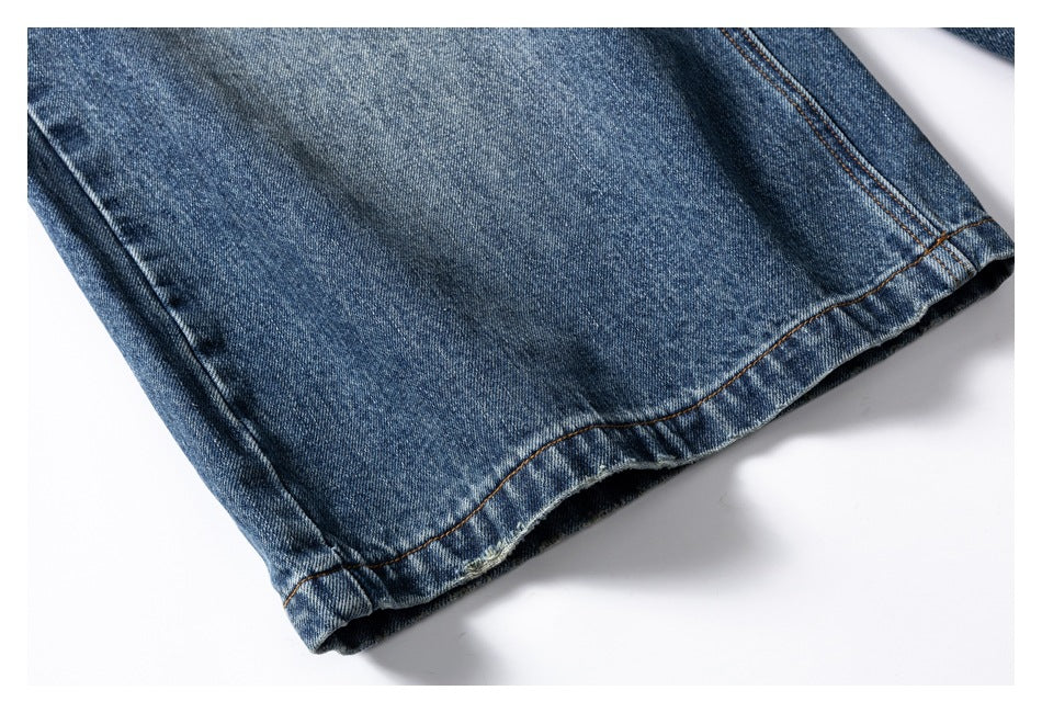 Close-up of a blue denim jean leg hem with contrasting brown stitching.